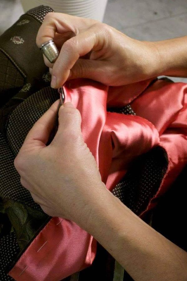 Le mani di Valeria Sechi mentre cuciono della seta rosa durante la realizzazione di una creazione Vipuntozero